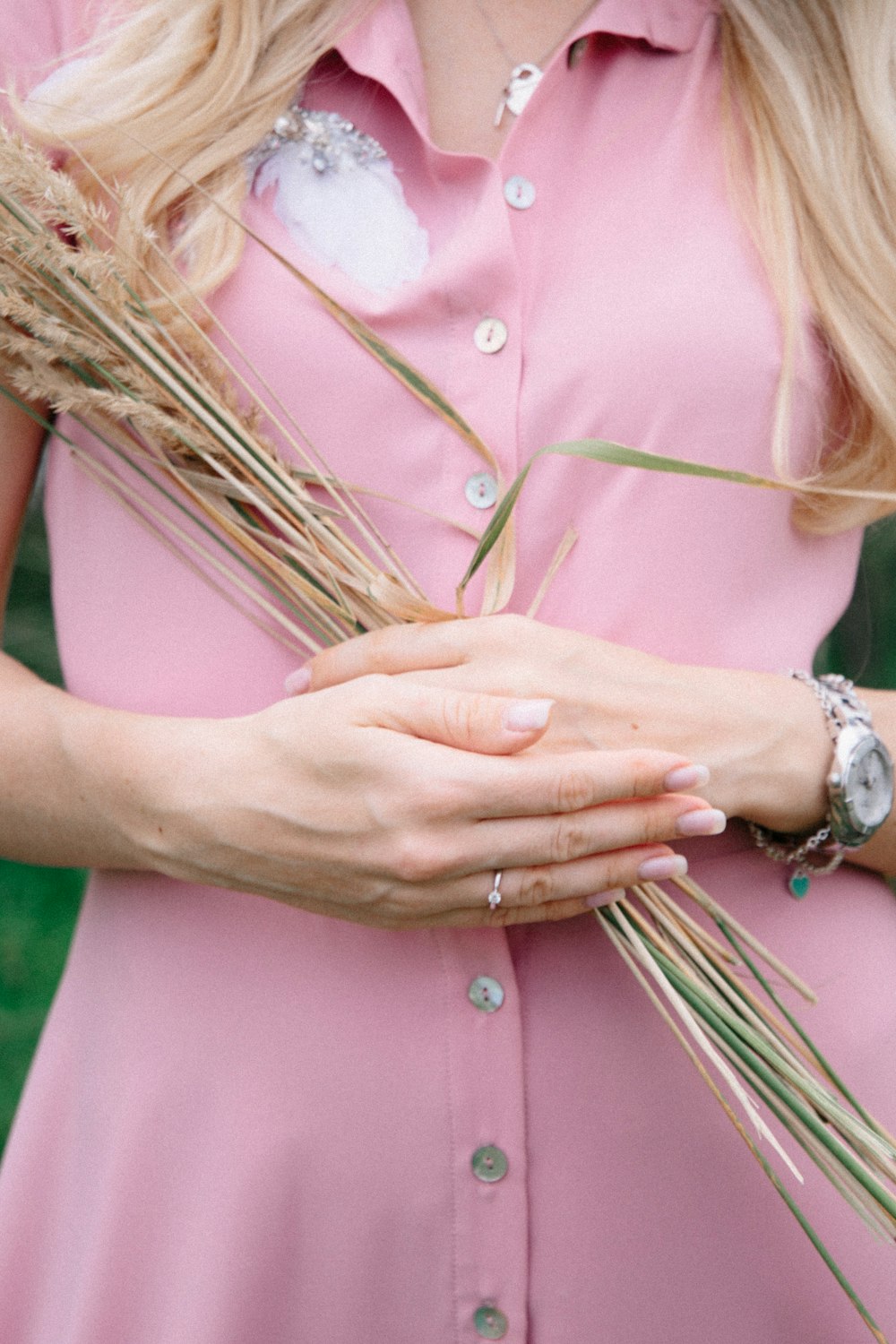 woman in pink button up shirt holding her chest