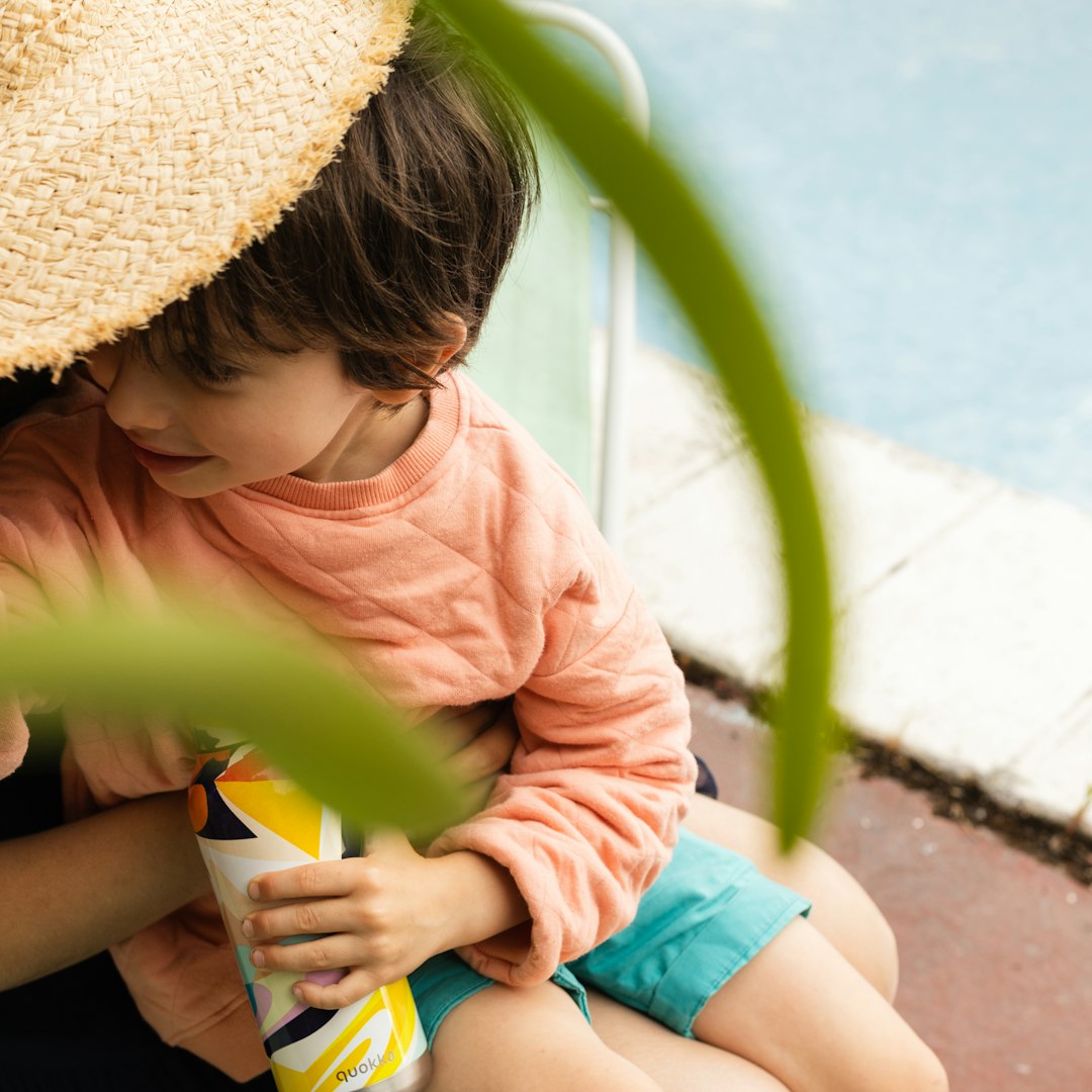 girl in pink shirt and blue shorts sitting on green and yellow plastic slide during daytime