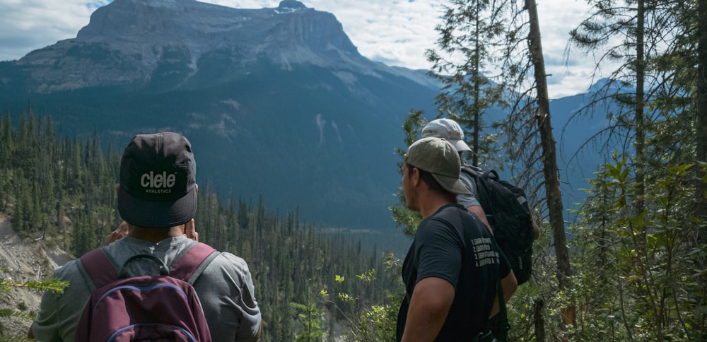 man in black t-shirt and gray cap standing near green trees during daytime