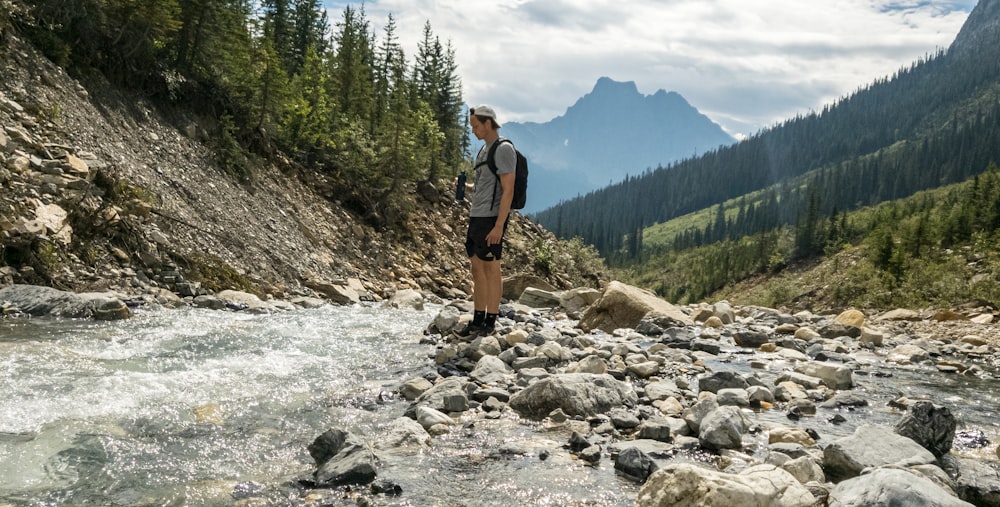 woman in black shirt and brown shorts standing on rocky ground during daytime