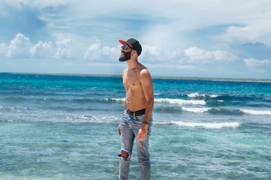 topless man in blue denim jeans standing on beach during daytime in La Romana Dominican Republic