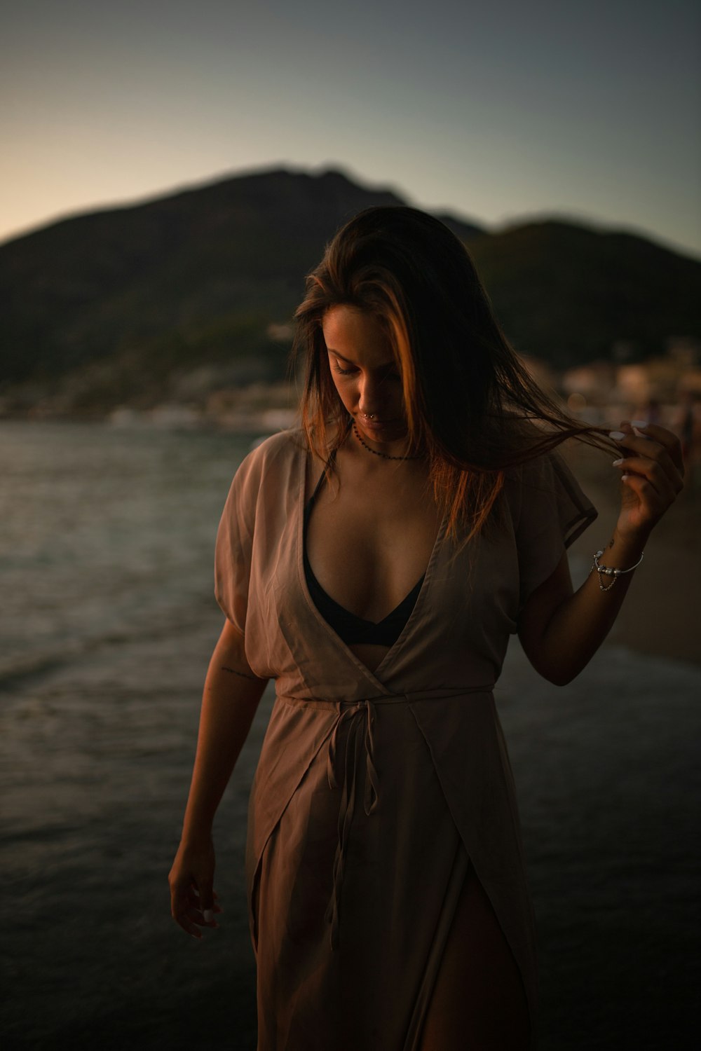 woman in brown spaghetti strap dress standing on beach shore during daytime