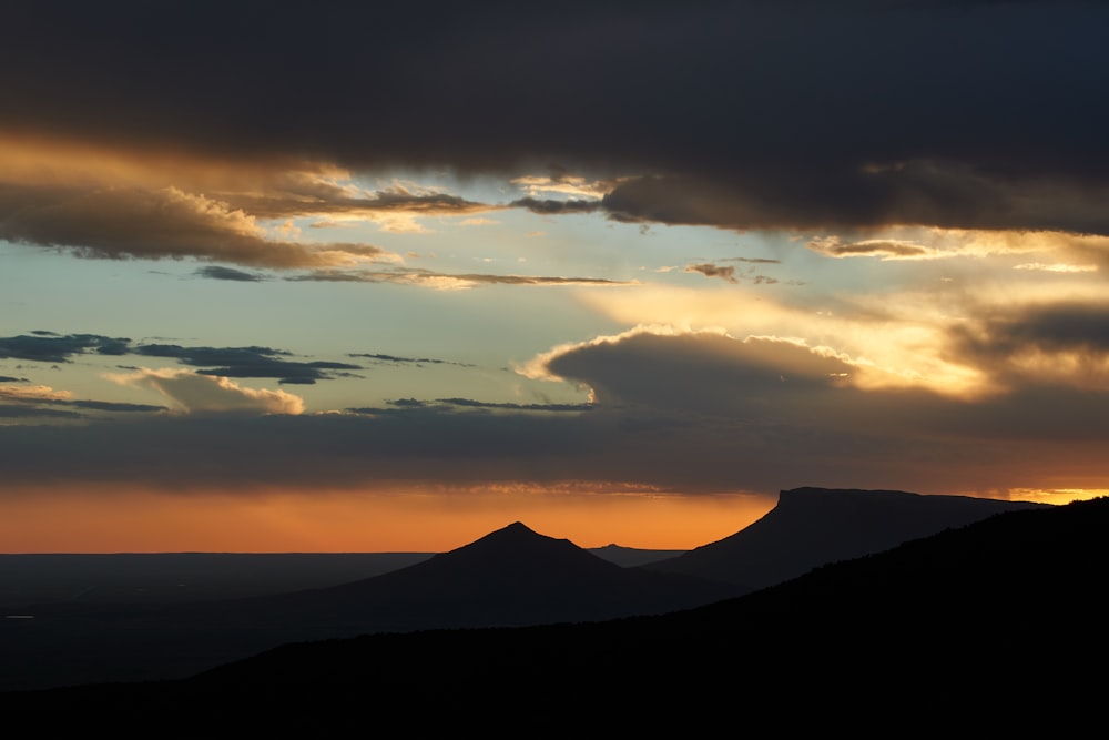 silhouette of mountain under cloudy sky during sunset