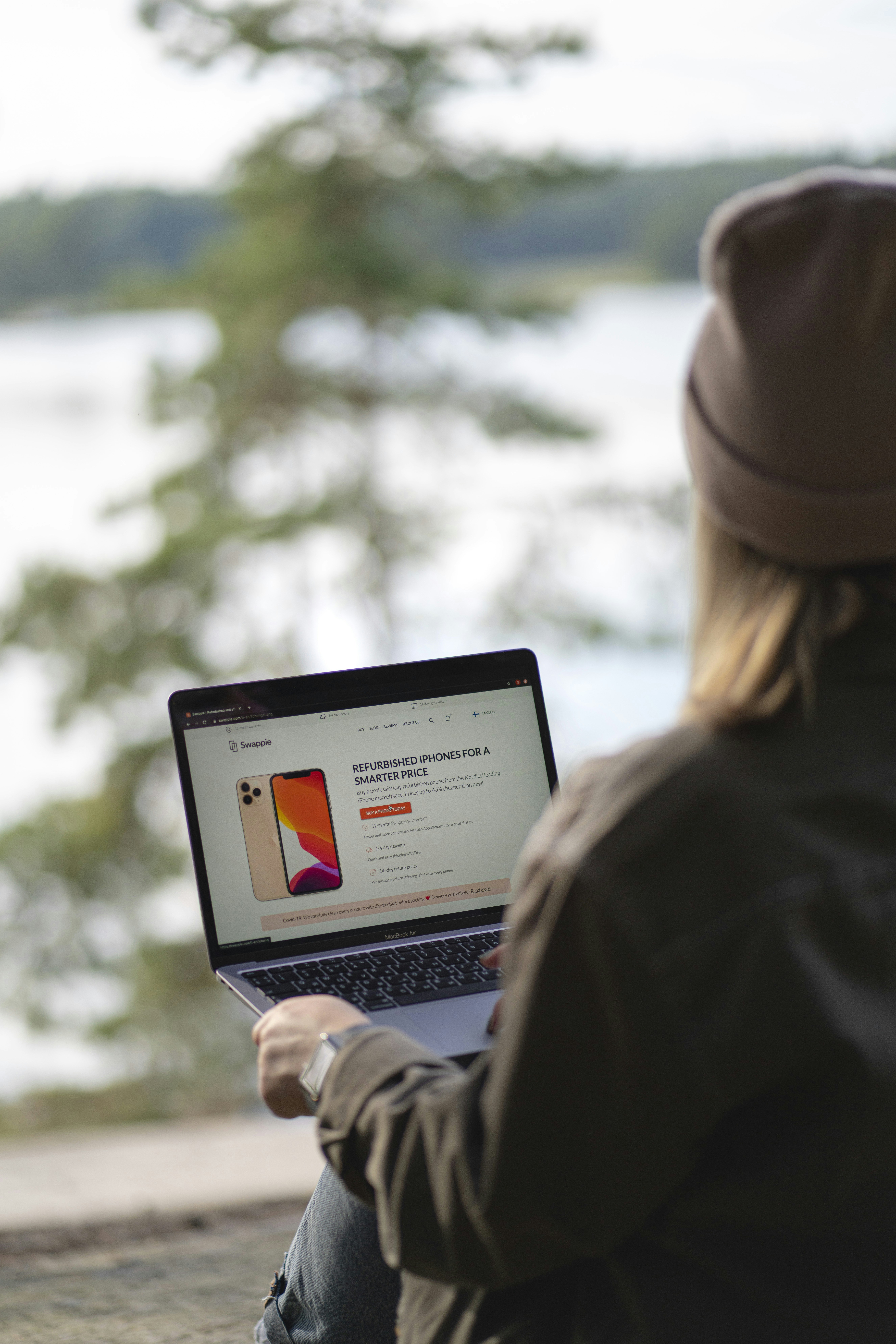 Wanita berjaket coklat menggunakan MacBook Pro