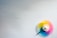 A colorful spinning top in motion creates a blur of vibrant colors against a plain white background. The motion effect adds a dynamic and playful element to the composition.