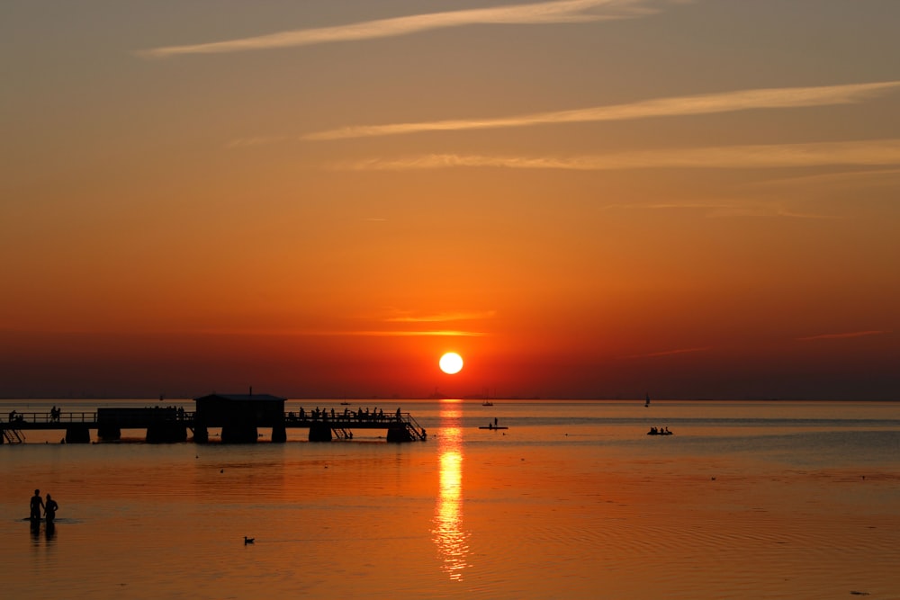 Silhouette de personnes sur la plage au coucher du soleil