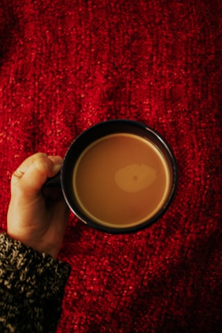 A person wearing cozy red gloves while holding a warm cup of coffee outdoors.