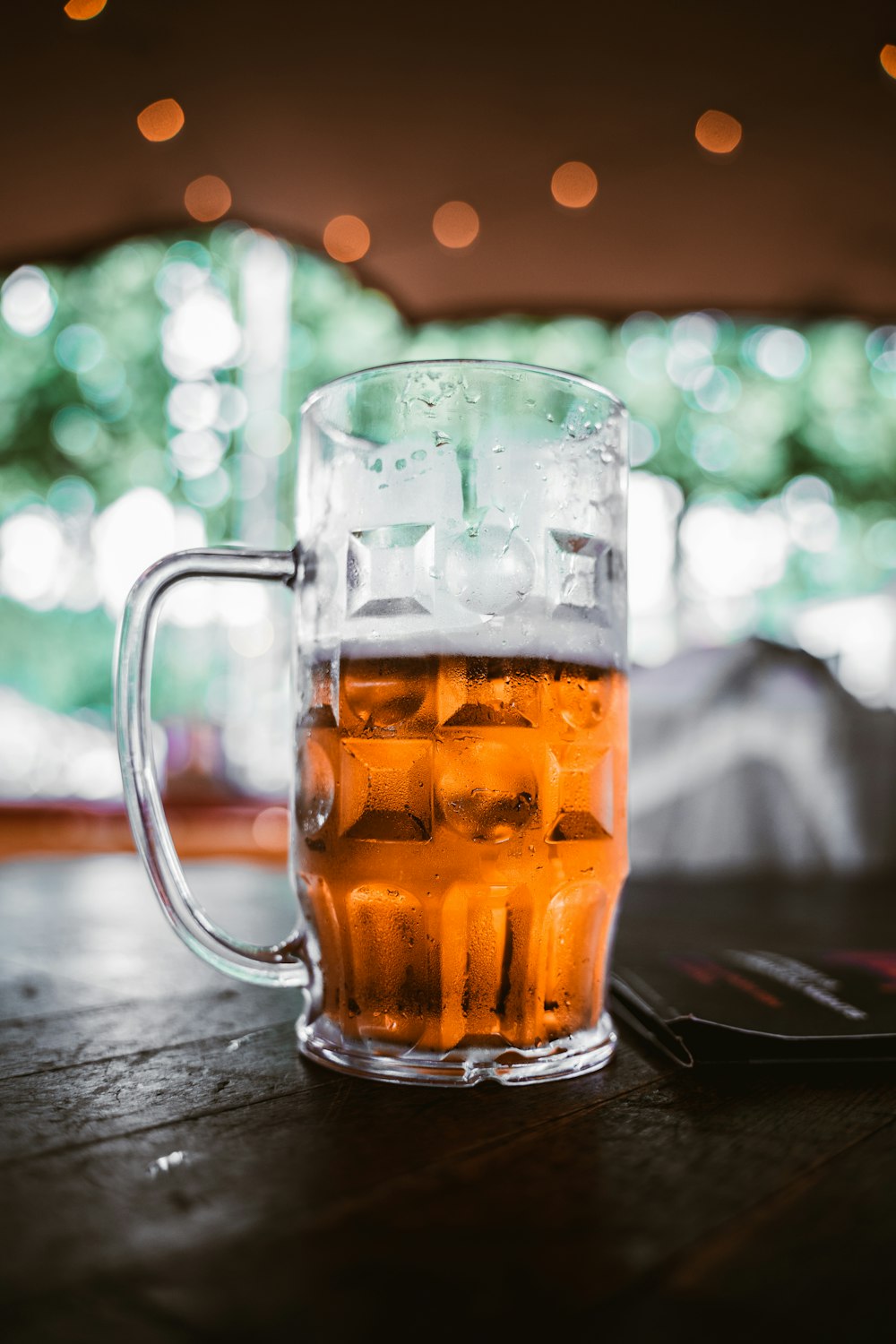 Tasse en verre transparent avec un liquide brun sur une table en bois brun