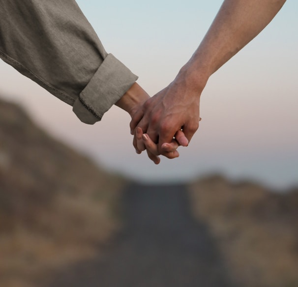 person in gray long sleeve shirt holding hands