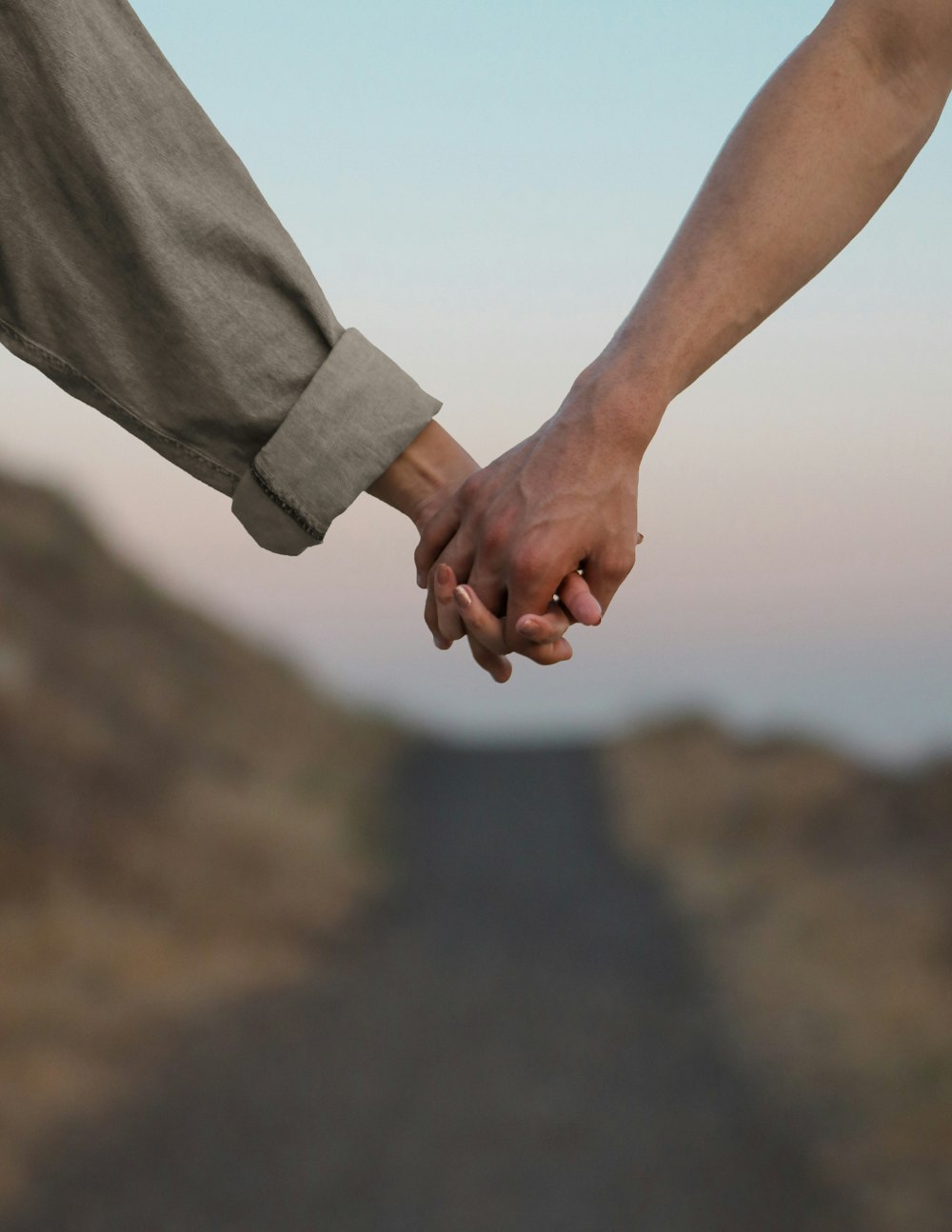 person in gray long sleeve shirt holding hands