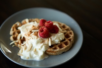 A warm, inviting shot of a waffle topped with pistachio cream and sprinkled with crushed nuts on a sky blue plate