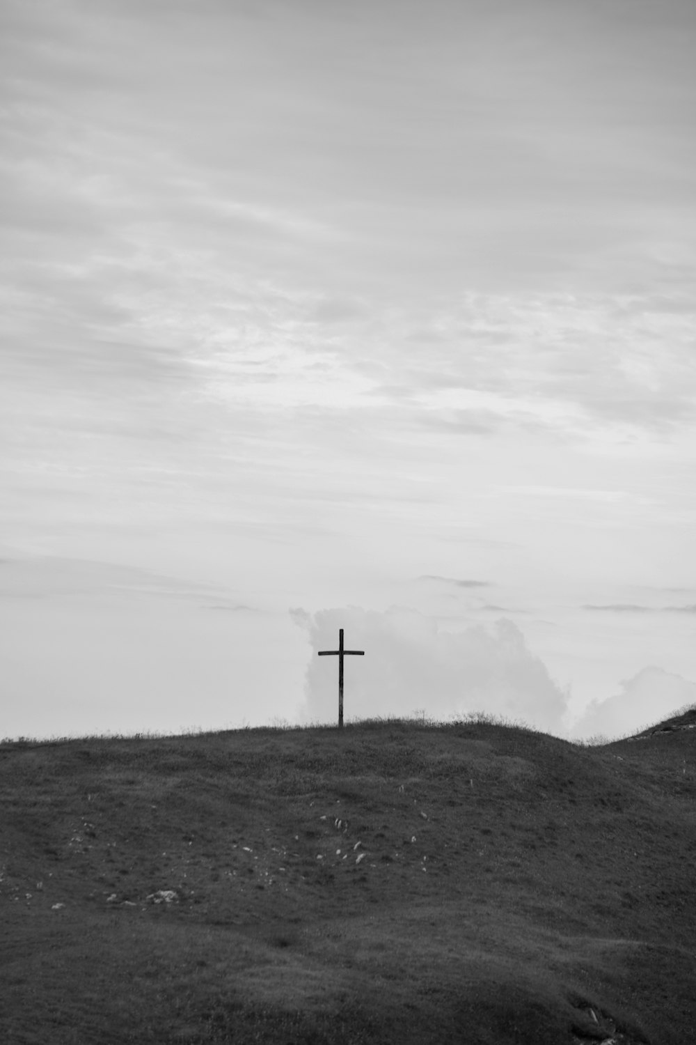 cruz cinzenta no campo verde da grama sob o céu branco durante o dia