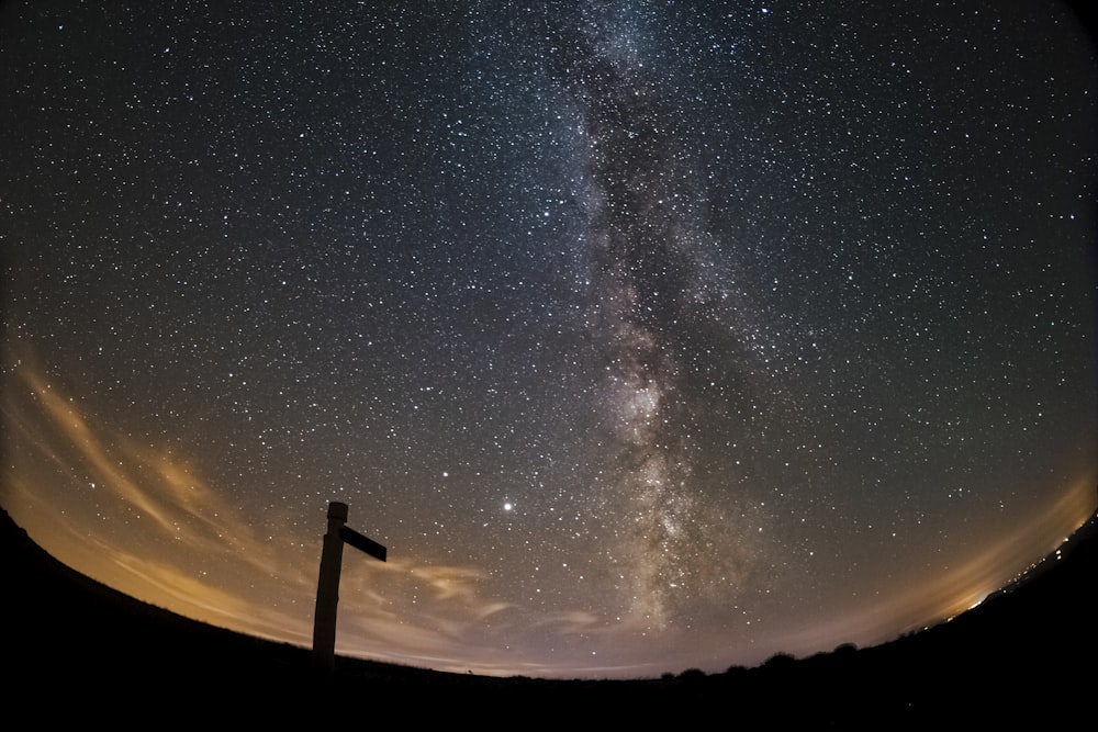 silhouette of man standing on top of the hill under starry night