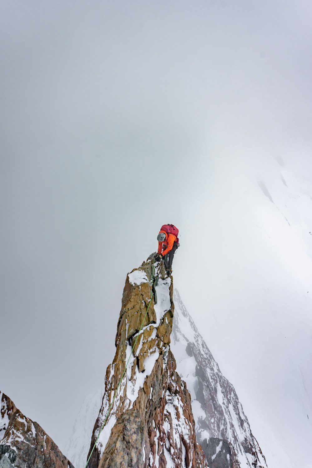 person in red jacket and black pants standing on snow covered ground during daytime