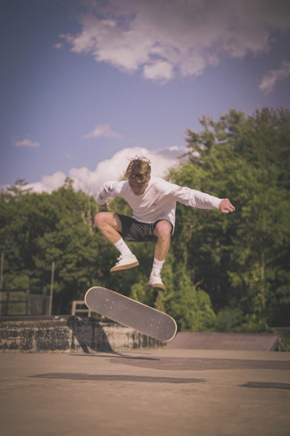man in white t-shirt and black pants doing skateboard stunts during daytime