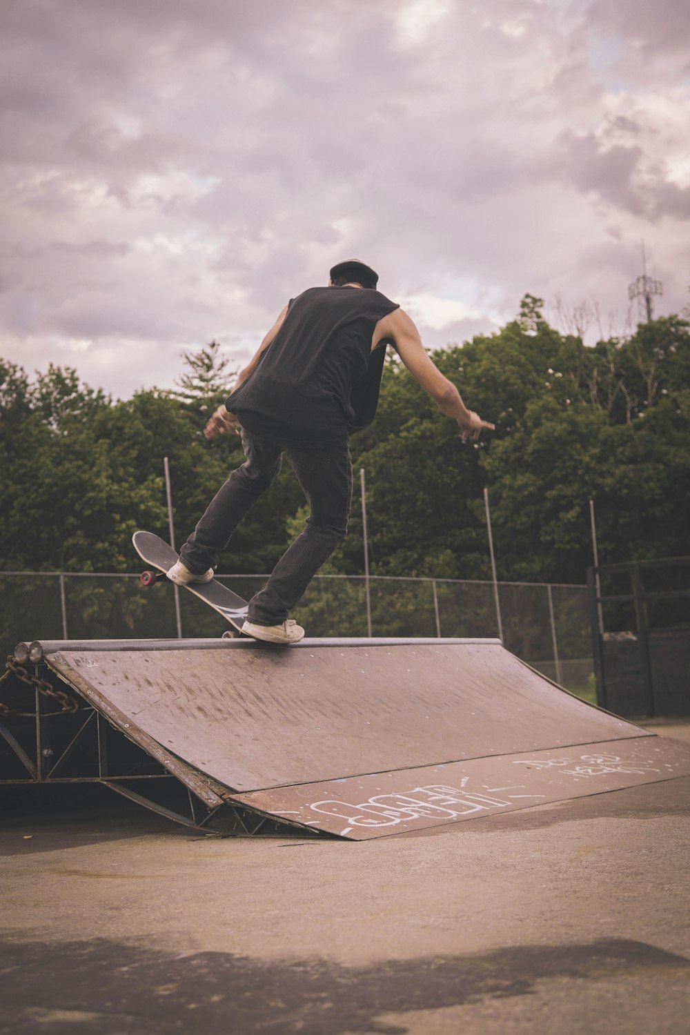 man in black t-shirt and blue denim jeans playing skateboard during daytime