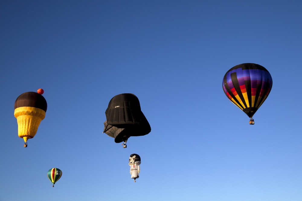 black hot air balloons on mid air under blue sky during daytime