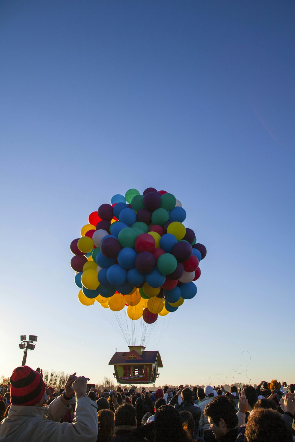 Eine große Gruppe von Menschen beobachtet ein Haus am Himmel fliegen