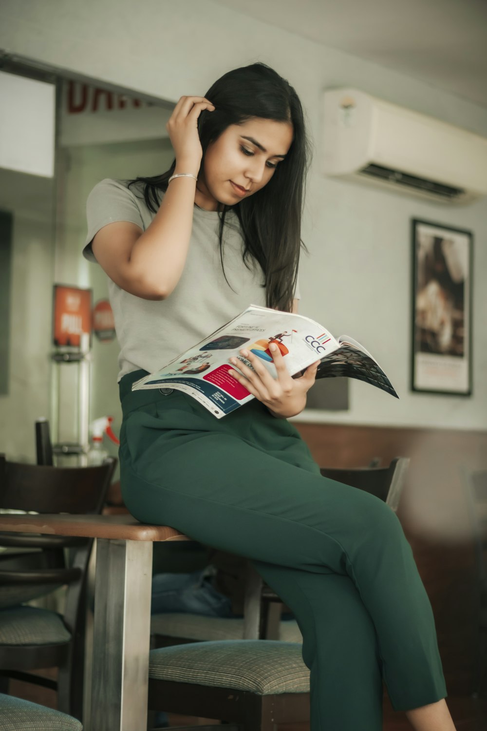 woman in white t-shirt and green pants holding white and red labeled pack