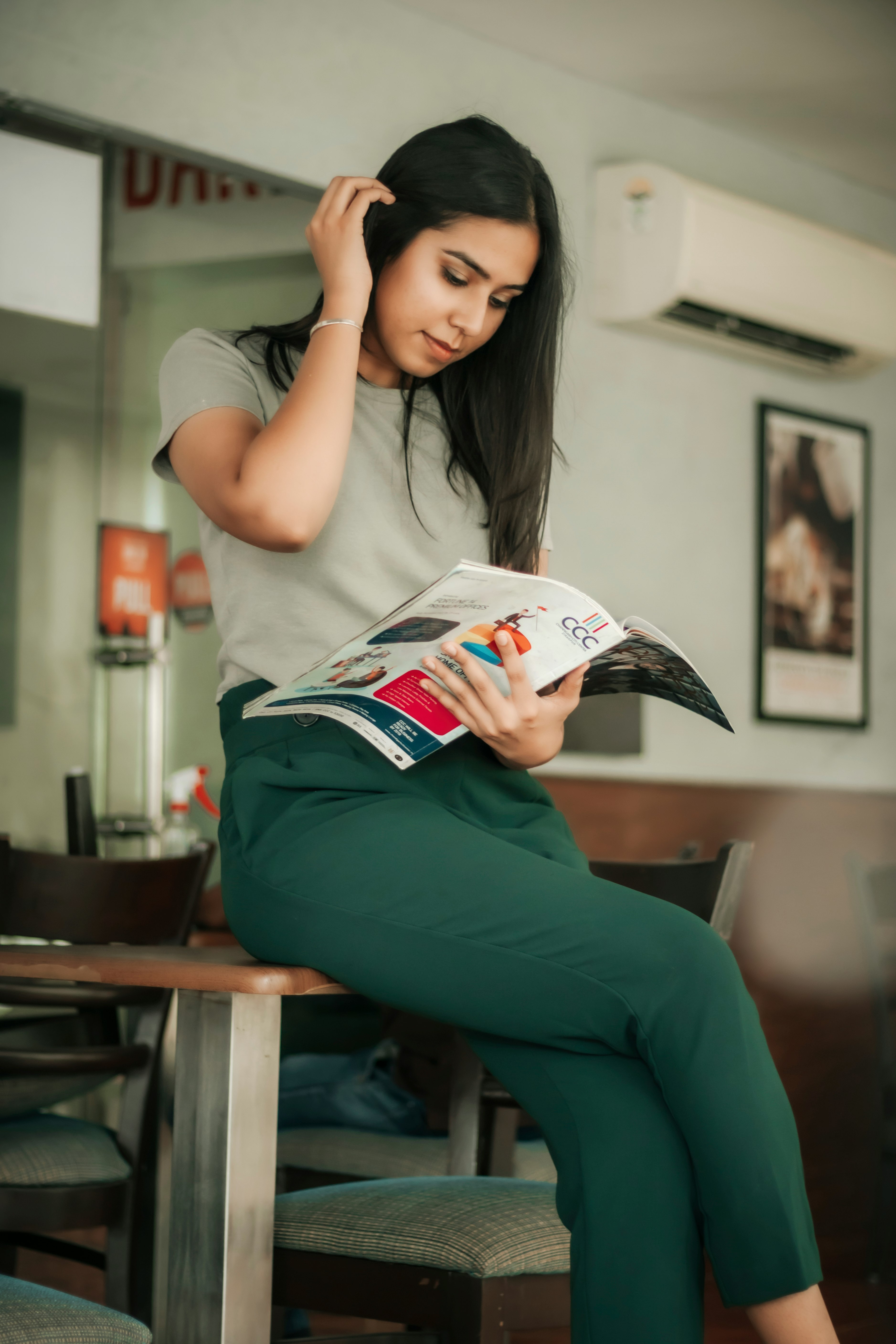 woman in white t-shirt and green pants holding white and red labeled pack