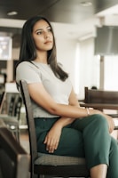 A woman thoughtfully reviewing her paycheck at a cozy kitchen table with soft pinkish-brown tones.