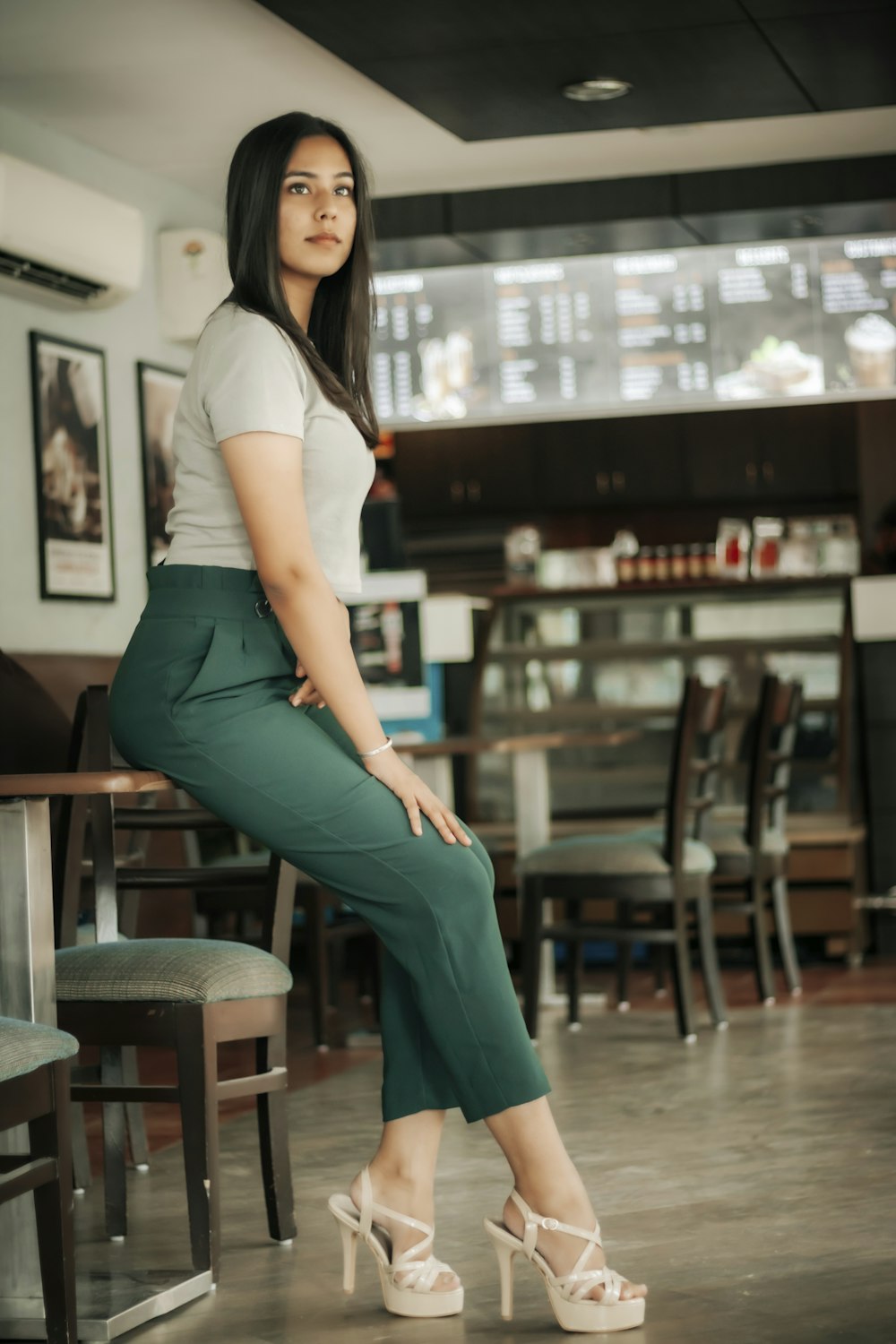 woman in white shirt and green pants sitting on bar seat