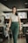woman in white shirt and green pants standing near black chair