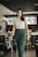 woman in white shirt and green pants standing near black chair