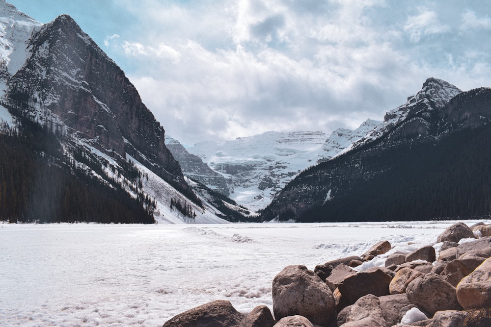 brown rocks on snow covered ground near snow covered mountains during daytime