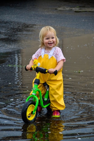 A joyful child riding a bright-colored bike in a sunny park.
