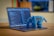 A laptop is displaying a programming code editor with multiple lines of colorful code. Beside the trackpad, there is a blue plush toy shaped like an elephant with the text 'php' embroidered on its side. The background is slightly blurred, showing hints of a cozy indoor environment.