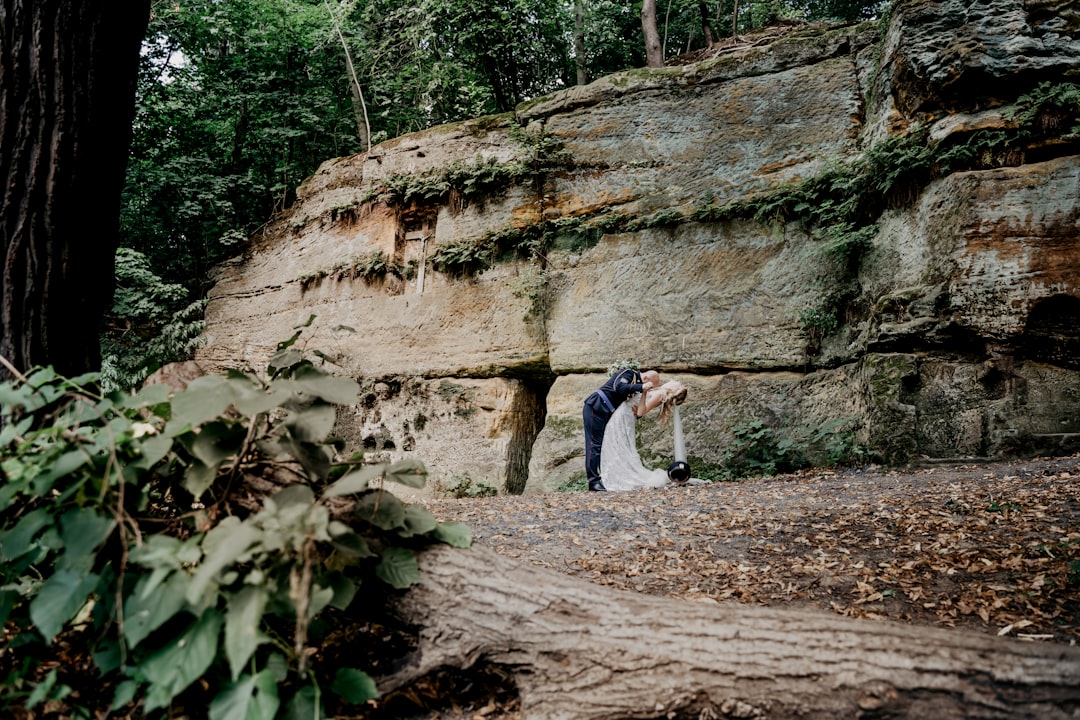 woman in blue jacket and blue denim jeans standing beside brown rock formation during daytime