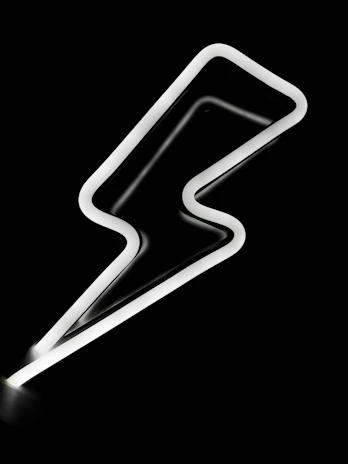 Creative team brainstorming around a table illuminated by a bold yellow neon light shaped like a lightning bolt.