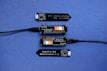 A series of electronic components displayed on a blue surface, including two black modules labeled 'Plant Wing' with colorful bar graphics and USB connectors. Two black capacitive soil moisture sensors version 1.2 are also present, with one shown connected via black cables.