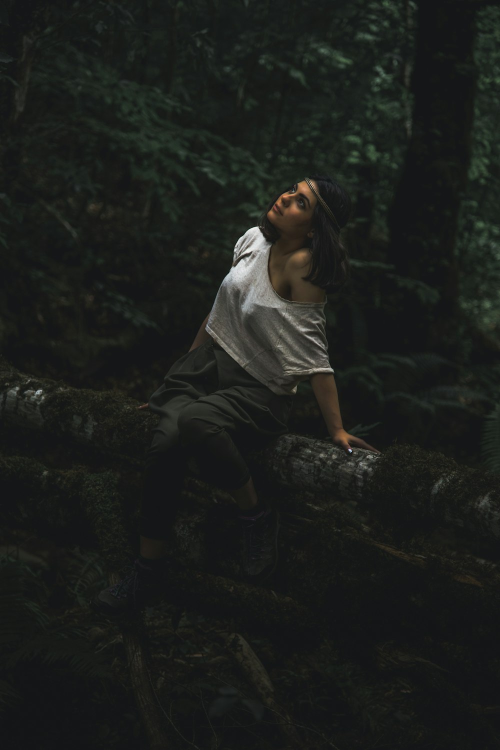 woman in white shirt and black pants sitting on rock