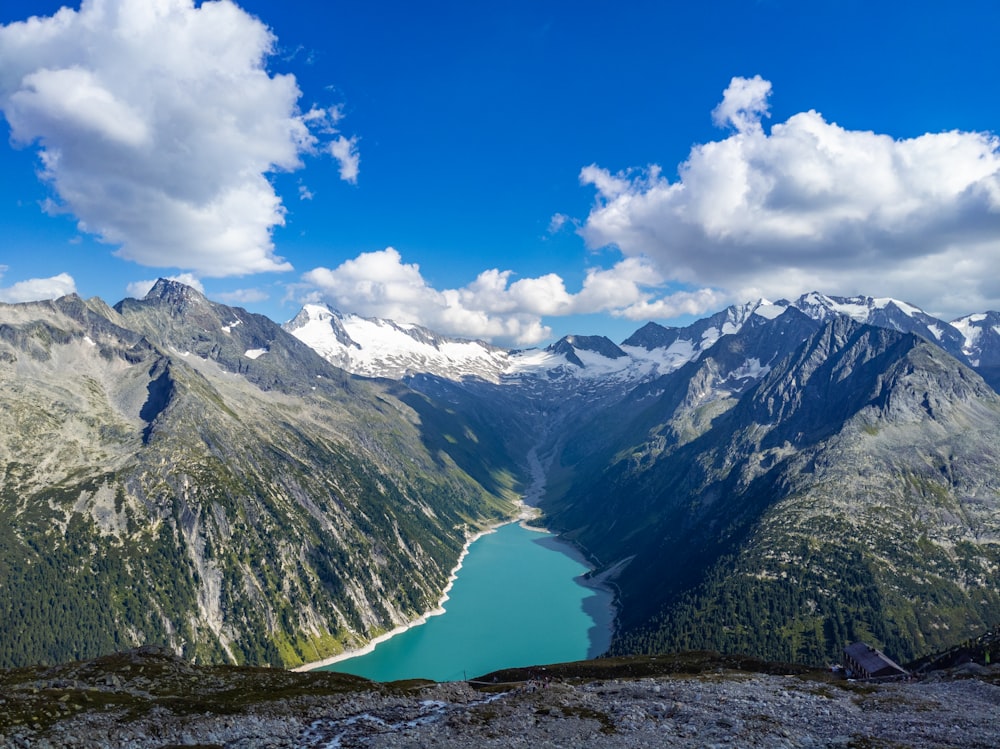 lake in the middle of mountains under blue sky and white clouds during daytime