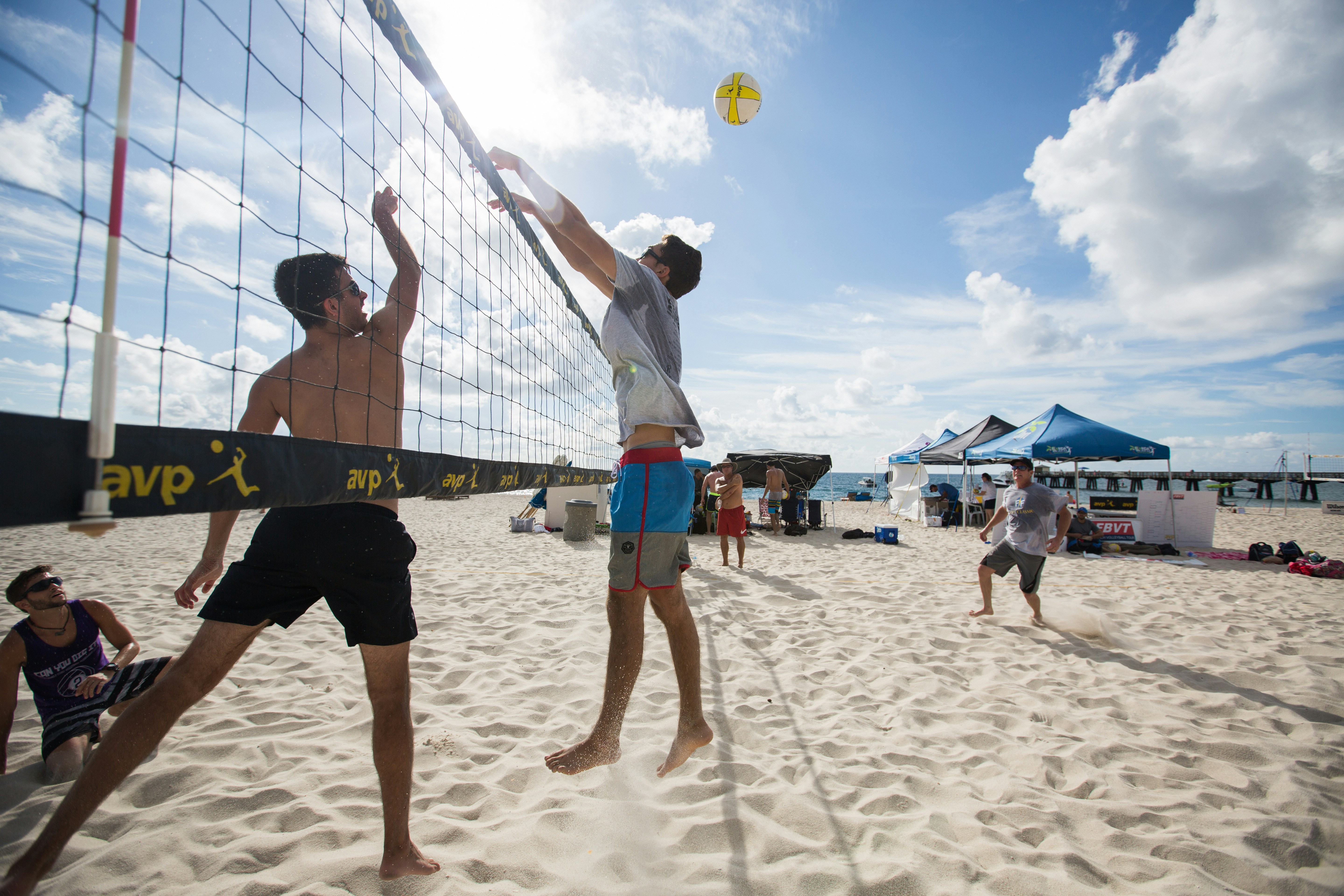 Two teams compete in beach volleyball.