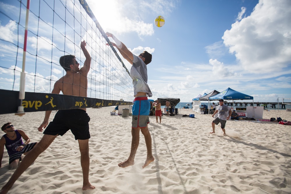 man in white shirt and blue shorts playing volleyball on beach during daytime