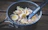 A close-up of a hearty freeze-dried meal rehydrating in a lightweight camping bowl on a rustic wooden table.