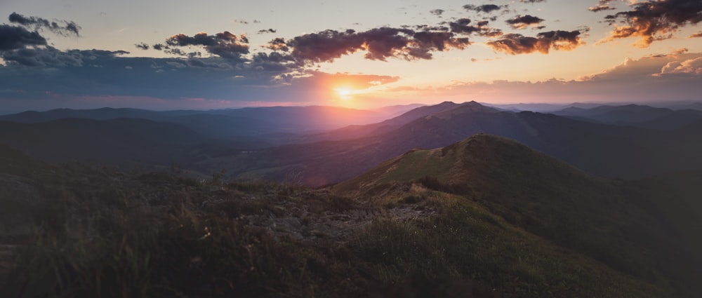 green grass field and mountains during sunset