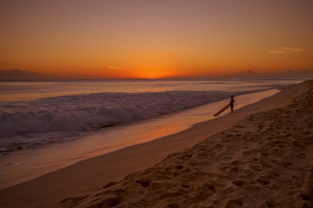Persona caminando en la playa durante la puesta del sol