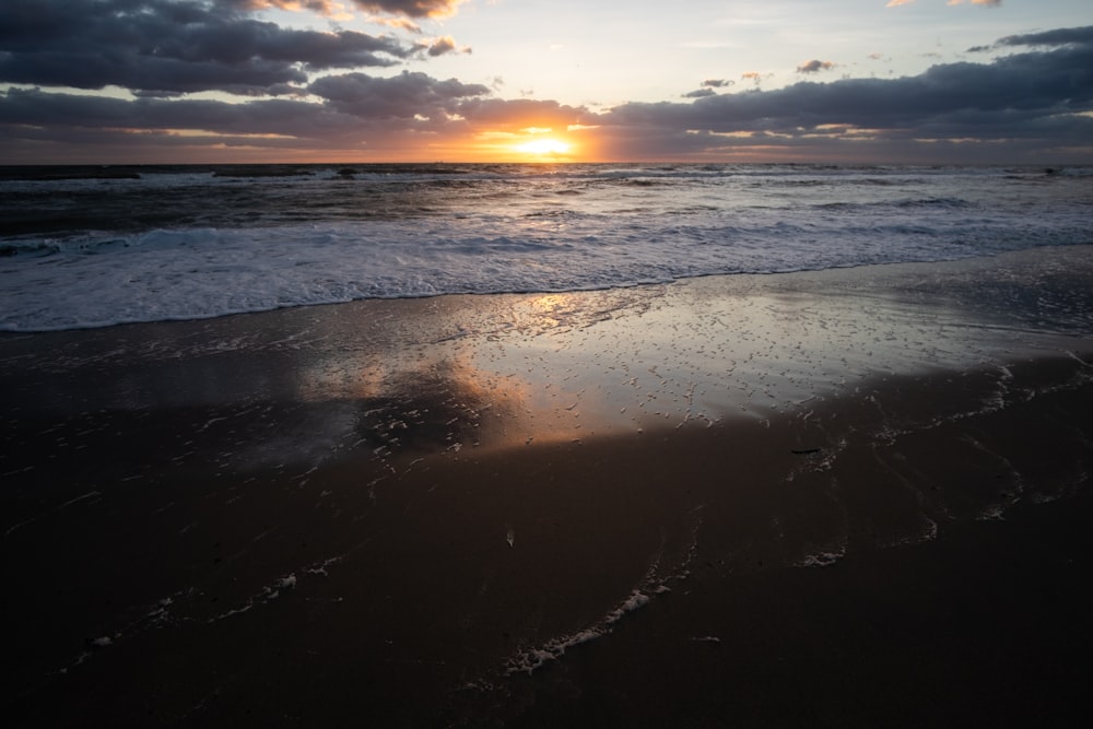 sea waves crashing on shore during sunset