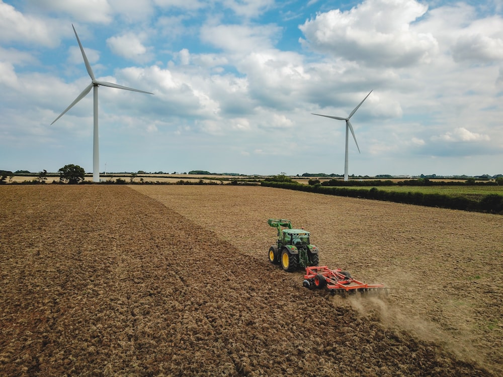 green and red tractor on brown field under blue and white cloudy sky during daytime