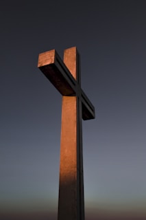 Soft morning light illuminating a simple cross mounted on a stone wall, symbolizing faith and reverence.