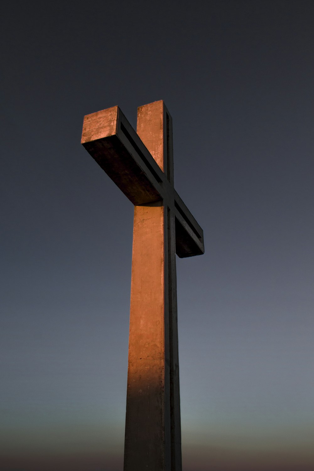 cruz de madeira marrom sob o céu azul durante o dia