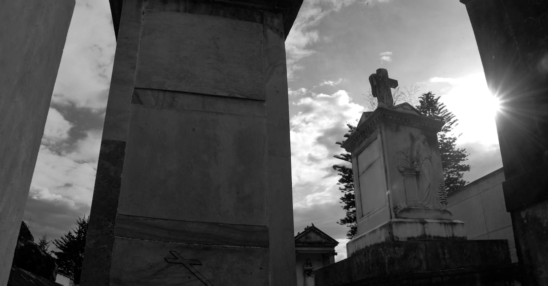 grayscale photo of statue of man on top of building