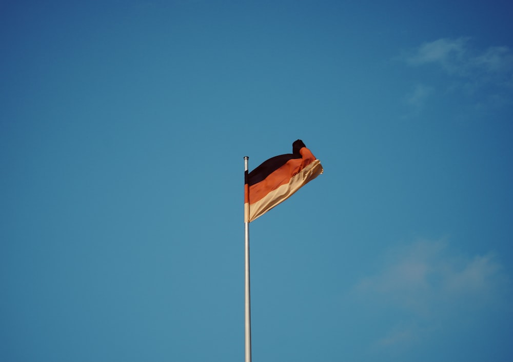 red white and yellow flag on pole under blue sky during daytime