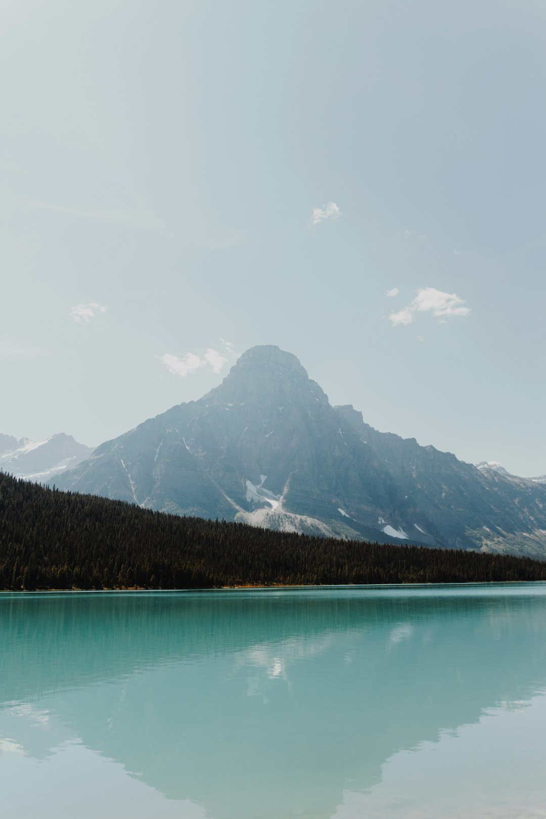 green lake near mountain under white sky during daytime