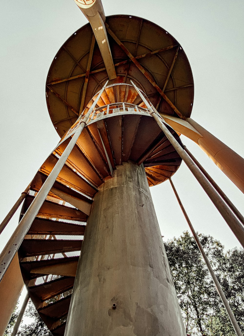 escada em espiral de madeira marrom sob o céu azul durante o dia