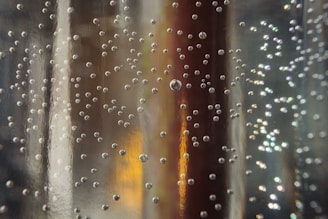 Close-up of a fizz tablet dissolving in a clear glass of water, releasing gentle bubbles.